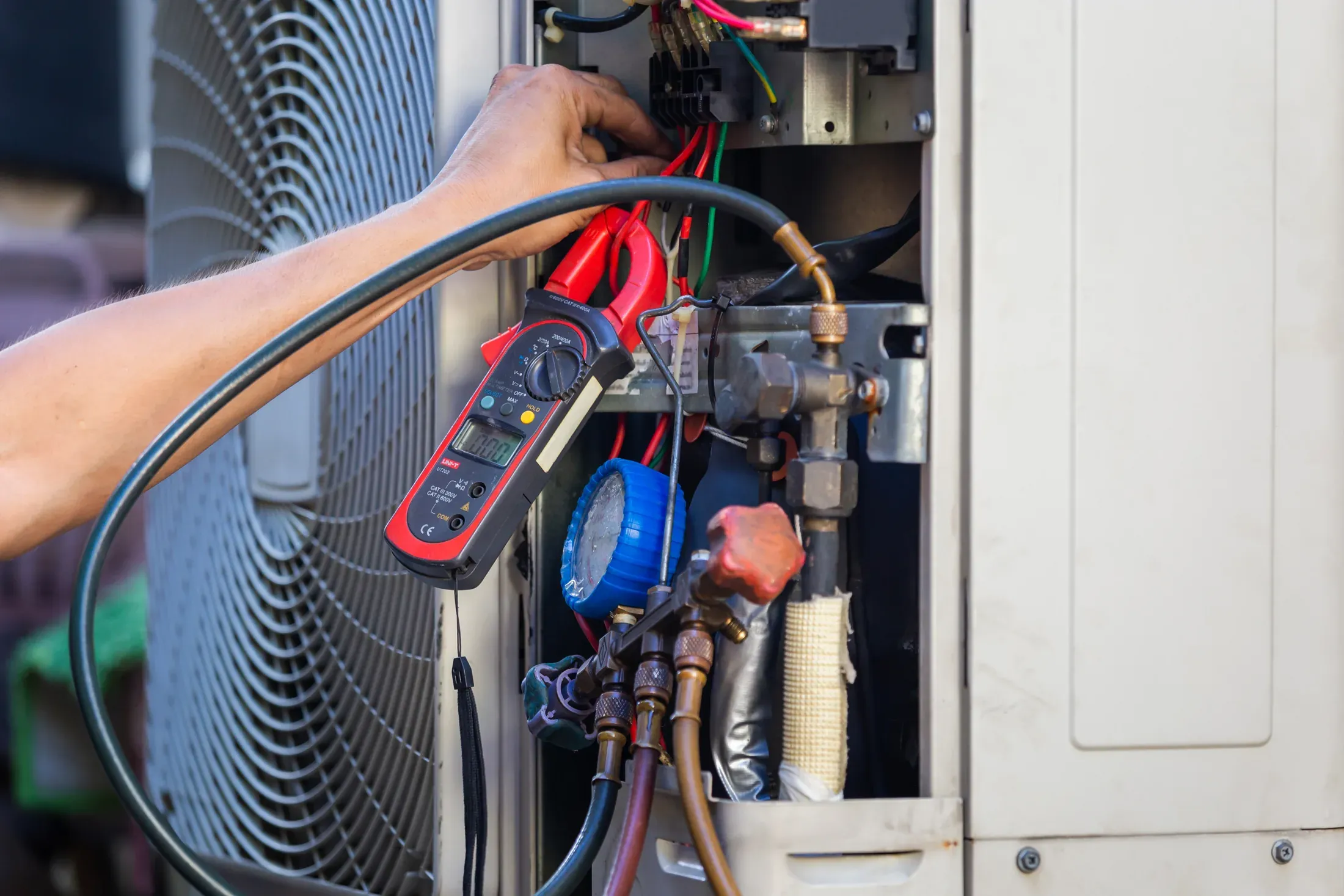 HVAC technician's hands checking and repairing refrigerant lines on an outdoor air conditioning unit